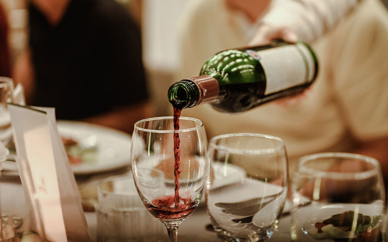 Waitress Is Pouring Red Wine In Glasses For Wine Tasting Event On The Table In Restaurant . Blurred Background. On Cloud Wine in Franklin, Wisconsin.